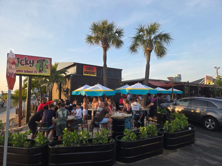 Ricky T's Bar & Grille sign and busy front patio with umbrellas in Treasure Island, FL Ricky T's Bar & Grille sign and busy front patio with umbrellas in Treasure Island, FL
