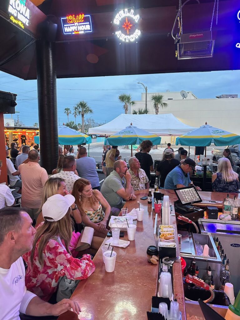 Packed bar counter with palms and blue sky at Ricky T's Treasure Island