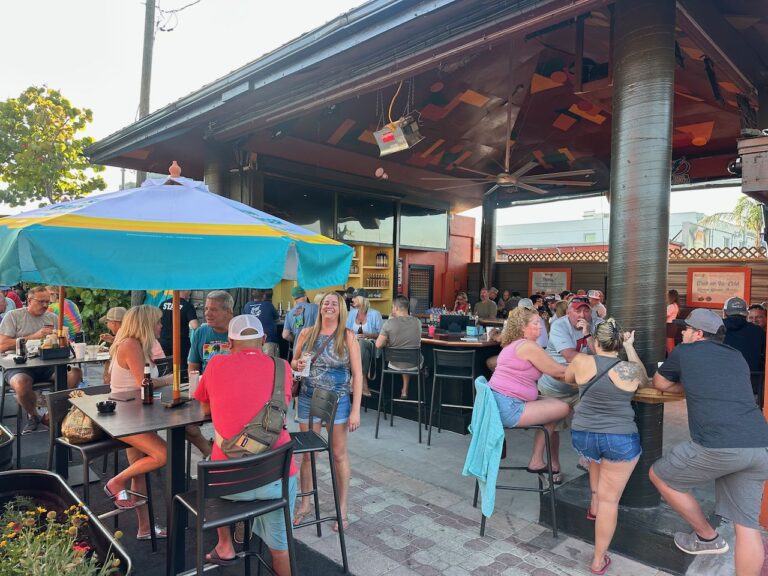 Daytime patio with a single teal-and-yellow umbrella at Ricky T's