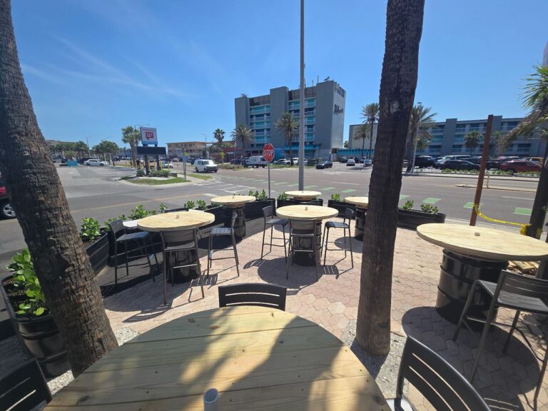 Patio tables among palm trees at Ricky T's Treasure Island